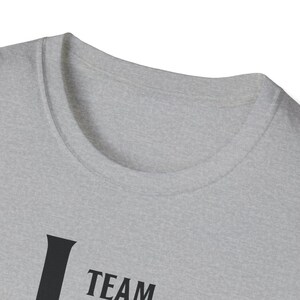 A close-up shot of the neckline of a light gray heather t-shirt with dark text visible near the bottom edge.
