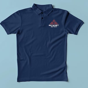 May include: Navy blue polo shirt with a collar and short sleeves. The shirt features a small logo on the left chest that reads "SKYNET HELP DESK" in white text with a red pyramid design above it.