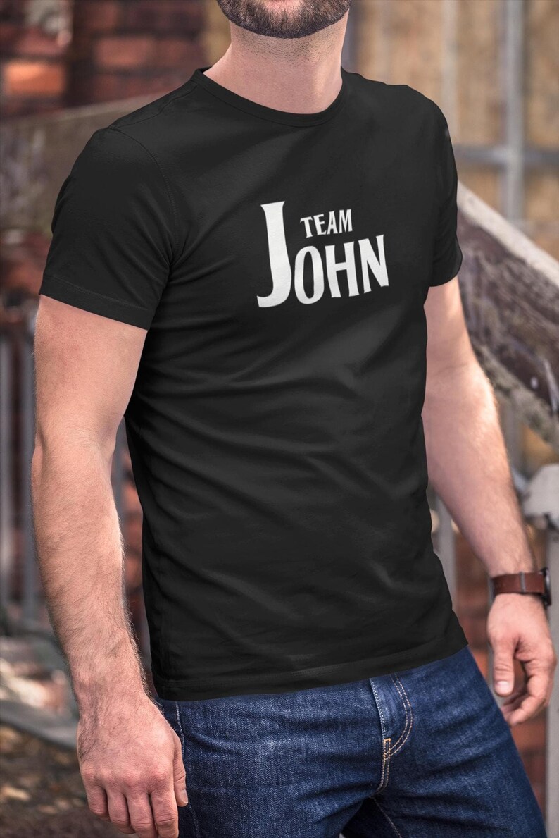 A person wearing a black t-shirt with Team John printed in white text on the front.