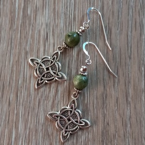 May include: A pair of silver-toned Celtic knot earrings with green stone beads. The earrings feature a four-leaf clover design with intricate knotwork. The ear wires are a simple hook style, and the beads are a muted green color.