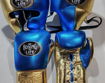 May include: A set of metallic blue and gold boxing equipment including two headgear pieces and two boxing gloves. Each item features a black oval patch with the text NO BOXING NO LIFE. The gloves have white lace-up closures and gold cuffs.