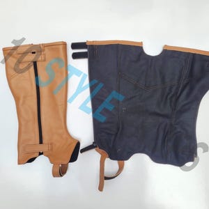 May include: A pair of equestrian half chaps, one in tan leather with a black vertical zipper and a bottom strap, and one in dark navy blue fabric with tan leather trim at the top, featuring side hook-and-loop fasteners and a bottom stirrup strap.
