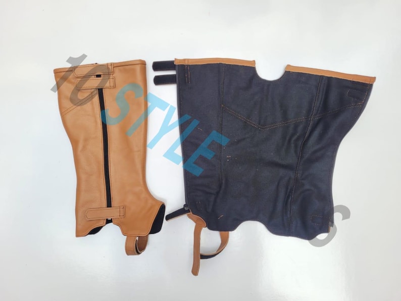 May include: A pair of equestrian half chaps, one in tan leather with a black vertical zipper and a bottom strap, and one in dark navy blue fabric with tan leather trim at the top, featuring side hook-and-loop fasteners and a bottom stirrup strap.