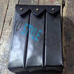 May include: A black leather pouch with three sections, each with a flap secured by a brass-coloured stud. The rectangular pouch is likely handmade. The text "10 STYLE PROPS" is visible in the image.