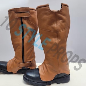 May include: A pair of tan leather gaiters with black vertical zippers and adjustable hook-and-loop straps, worn over black boots. The text 10 STYLE PROPS is overlaid across the image. The gaiters feature a textured finish and a cutout at the top.