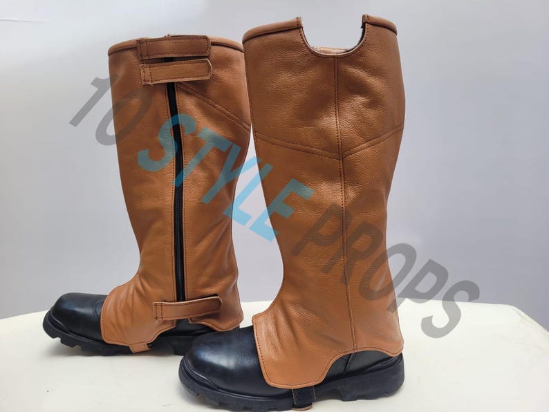 May include: A pair of tan leather gaiters with black vertical zippers and adjustable hook-and-loop straps, worn over black boots. The text 10 STYLE PROPS is overlaid across the image. The gaiters feature a textured finish and a cutout at the top.
