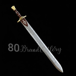 May include: A silver and brown sword with a gold hilt and a brown handle. The blade has a decorative design. The sword has a brown emblem on the guard. The text "80 Brand Cutlery" is at the bottom.