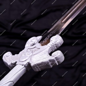 May include: A silver-colored sword with an ornate handle and a long, pointed blade. The handle features a detailed design, and the blade has a subtle pattern. The sword is displayed against a dark background.