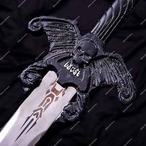 May include: A black sword with a skull and wing design on the hilt. The blade is silver with a brown and black pattern. The word "baust" is written in white on the hilt.
