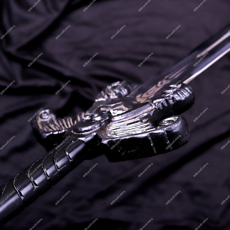 May include: A black sword with a detailed dragon-shaped hilt. The blade is silver and the handle is wrapped in a textured pattern. The sword is set against a dark background, highlighting its intricate design.
