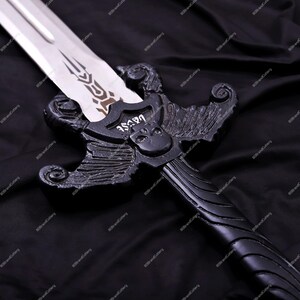 May include: A black fantasy sword with a silver blade. The hilt features a skull and wing design with the word "fuwang" on the guard. The sword is set against a black background.