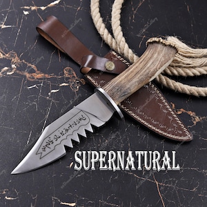 May include: A stainless steel knife with a serrated edge and a deer antler handle. The knife is in a brown leather sheath with a matching belt loop. The word "SUPERNATURAL" is displayed below the knife.