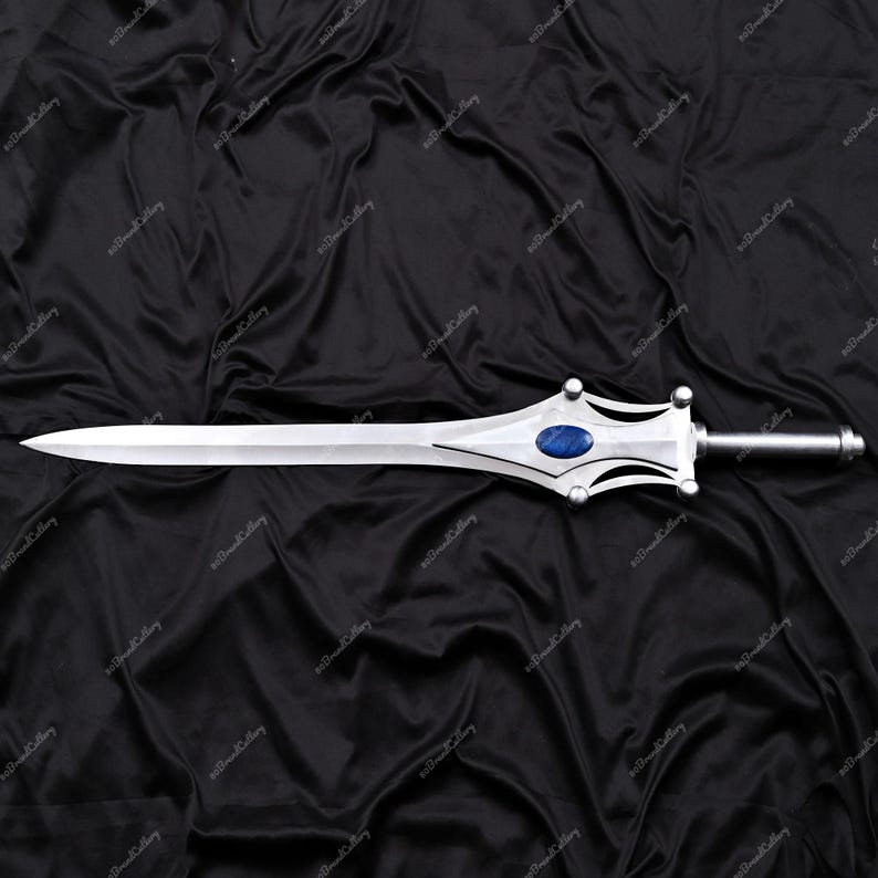 Puede incluir: Una espada plateada con una hoja puntiaguda y una guarda decorativa. La guarda presenta una gema ovalada azul y un mango plateado. La espada se muestra sobre un fondo negro texturizado.