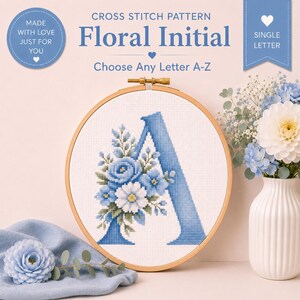 Peut inclure: Un motif de point de croix avec la lettre "A" orné de fleurs bleues, présenté dans un cercle à broder en bois. Le motif comprend le texte "Floral Initial" et "Choose Any Letter A-Z".