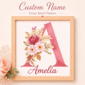 May include: A framed cross stitch pattern featuring a large pink letter A decorated with a cluster of pink and red flowers and green leaves. The name Amelia is stitched in cursive script below the letter. The text Custom Name Cross Stitch Pattern appears above the frame.