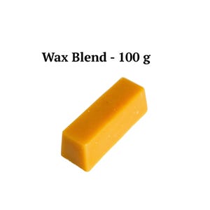 Puede incluir: Un bloque rectangular de mezcla de cera amarilla, con el texto "Wax Blend - 100 g" encima. La cera es de un color sólido y opaco y parece recién cortada. El fondo es blanco liso.