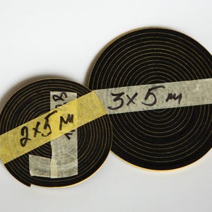 May include: Two rolls of black self-adhesive weather stripping with yellow tape labels. The larger roll has a label that says "3 x 5 m". The smaller roll has a label that says "2 x 5 m".