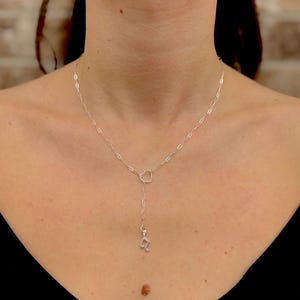 May include: A silver necklace with a heart-shaped pendant and a music note charm.
