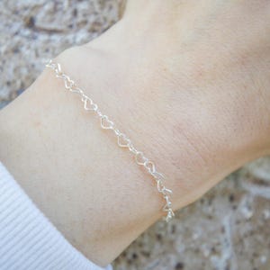 May include: A silver bracelet with a delicate heart-shaped chain.