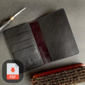 May include: Black leather passport holder with multiple card slots and a red interior. The holder has a stitched edge and a logo that says "Cult."  A PDF download icon is in the lower left corner of the image.