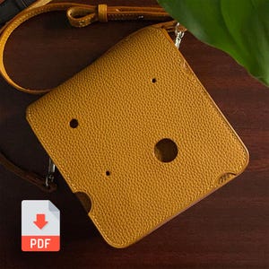 May include: Mustard yellow leather phone case with a crossbody strap. The case has a textured surface and three circular cutouts. The PDF icon is in the lower left corner. The strap is a lighter shade of yellow.
