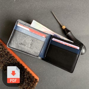 May include: Open black leather wallet with blue accents, holding cards and cash. The wallet has the "Suri Leather" logo embossed on the front. A leather working tool and a brush are next to the wallet.