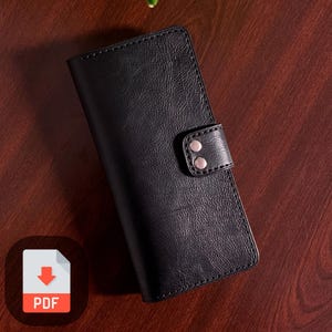 May include: Black leather wallet with a snap closure and two silver metal studs. The wallet has a textured surface.