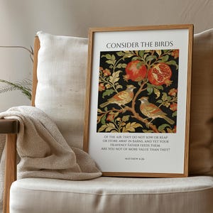 Op de afbeelding: Een ingelijste kunstafdruk met een botanisch ontwerp. Twee vogels zitten op een tak met granaatappels. De tekst "CONSIDER THE BIRDS" staat bovenaan, met daaronder een bijbelvers. De lijst is lichtbruin.