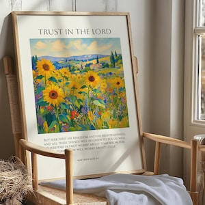 May include: A framed wall art print featuring a vibrant impressionist painting of a sunflower field under a blue sky. The text reads TRUST IN THE LORD at the top and includes the scripture Matthew 6:33-34 at the bottom in black lettering.