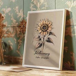 Può includere: Stampa incorniciata con un'illustrazione dettagliata di un girasole nei toni del giallo, arancione e marrone. L'opera d'arte include il testo "3rd Anniversary" e "Sunflower - Growing Together" su uno sfondo neutro, in una cornice bianca.
