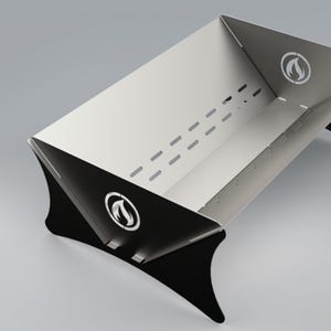 Pode incluir: Uma lareira de aço inoxidável com pernas pretas e um logotipo de uma chama em um círculo. A lareira tem uma borda elevada e uma série de furos ao longo da parte inferior.