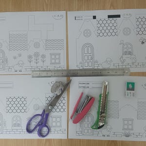 May include: Four white paper sheets with black line art of houses for assembly, featuring a 12-inch metal ruler, purple scissors, a pink stapler, a green utility knife, and a small white eraser. Each sheet includes CAD branding and folding lines.