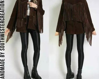 May include: A brown suede jacket with fringe detailing. The jacket has a button closure and two pockets. The model is wearing black leggings and black platform boots.