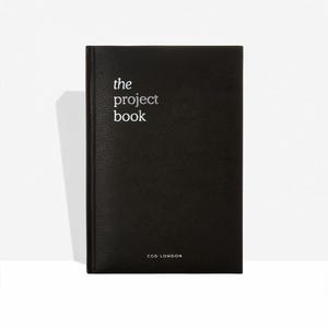 May include: A black notebook with the words "the project book" in white lettering on the cover. The notebook has a minimalist design, with the text "CGD LONDON" printed at the bottom.