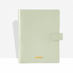 May include: A light green, faux crocodile-textured planner with a gold-colored rectangular accent that reads "COCO LONDON". The planner has a matching tab closure on the right side.