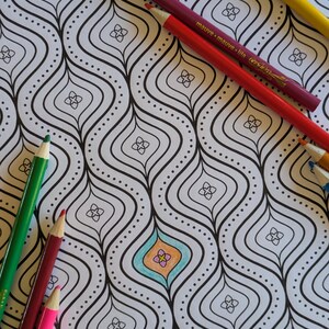 Op de afbeelding: Een zwart-witte kleurplaat met een herhalend patroon van gebogen lijnen en kleine vierkanten. De pagina is gedeeltelijk gekleurd met blauwe, oranje en roze kleurpotloden.