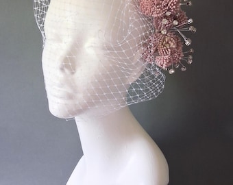 Tocado con flores suculentas de sedum púrpura, ramilletes de diamantes de imitación y velo tipo jaula de pájaros.