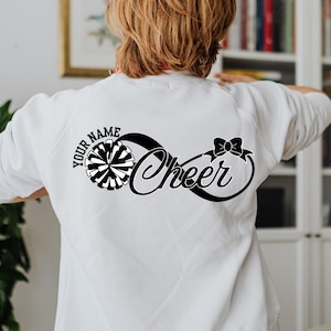May include: White sweatshirt with a black infinity symbol design that says "Cheer" and includes a black and white pom-pom. The text "Your Name" is above the design.