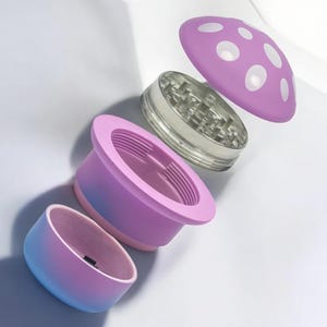 Exploded view of a pink and blue mushroom grinder with four separate parts, including a polka-dot cap, metal teeth chamber, filter, and storage – a cute and funny spice grinder perfect for herbs or seasoning.