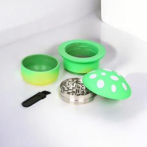 Cute green mushroom-shaped herb and spice grinder with four parts, including a metal grinding chamber, mesh screen, and cleaning brush – a funny and colorful grinder perfect as a unique kitchen or smoking accessory.