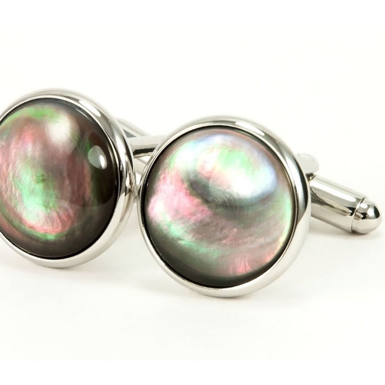 May include: A pair of silver cufflinks with iridescent black mother of pearl round insets.