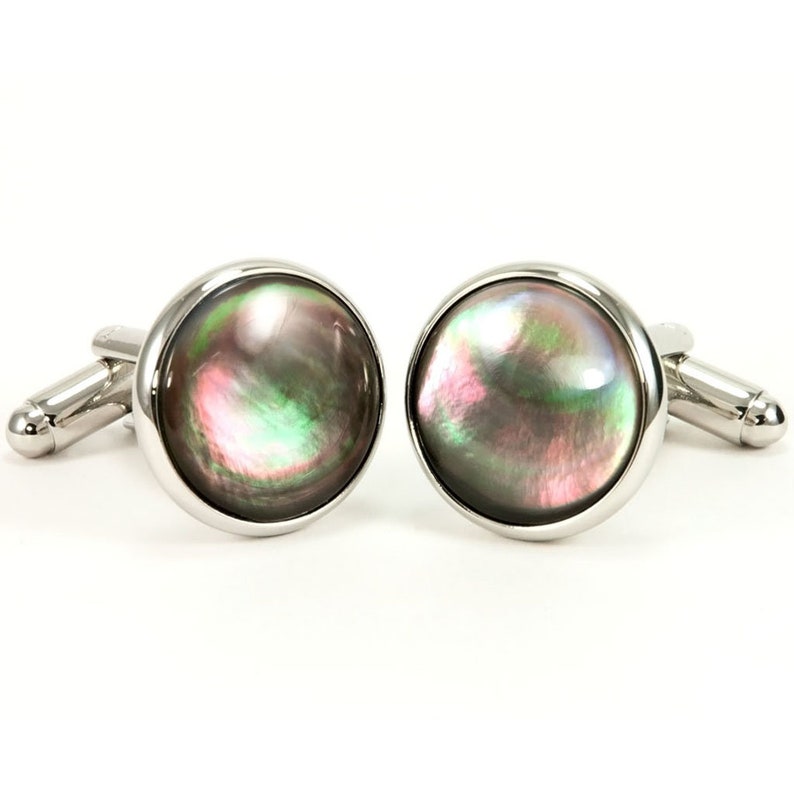 May include: A pair of silver cufflinks with round, iridescent black, green, and pink mother-of-pearl insets.