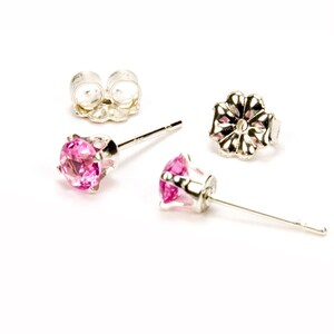 May include: A pair of silver stud earrings with pink gemstones. The earrings have a simple design and are perfect for everyday wear.