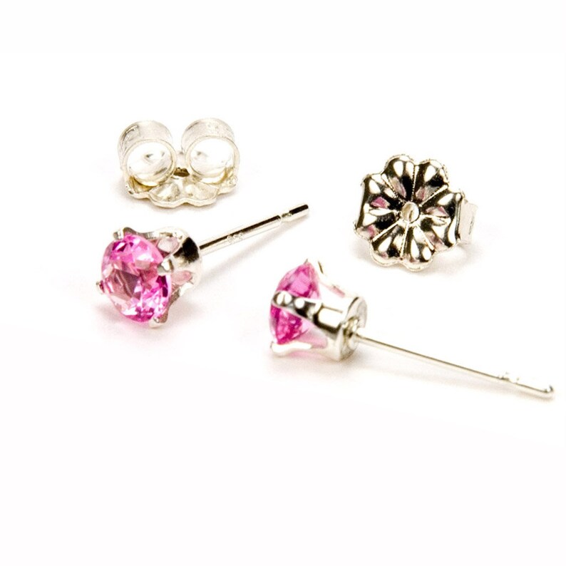 May include: A pair of silver stud earrings with pink gemstones. The earrings have a simple design and are perfect for everyday wear.