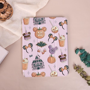 Könnte beinhalten: Eine hellviolette Tablethülle mit einem wiederkehrenden Halloween-Muster aus Spukhäusern, Kürbissen, kandierten Äpfeln, Ohren-Haarreifen, Fledermäusen, Zuckermais und Getränken mit Sahnehaube. Der Text BOO ist in Schwarz neben einem Haus aufgedruckt.