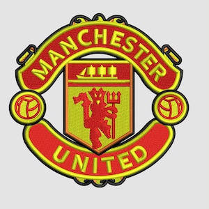 May include: Embroidered Manchester United crest in red, yellow, and black. The crest features a shield with a red devil holding a trident, surrounded by the words "Manchester United" and "United". Two circular emblems flank the crest.