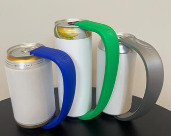 May include: Three aluminum beverage cans with different colored silicone handles. The handles are blue, green, and gray. The cans are white with a gold top and bottom.