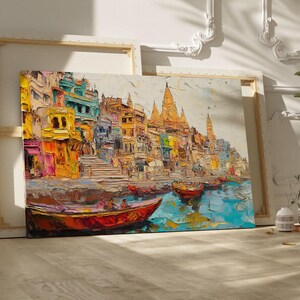 May include: A colorful painting of a cityscape with buildings and temples along a river. The painting features boats on the water and a bright blue sky.