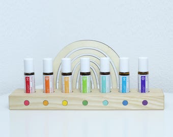 May include: Wooden roller bottle holder with seven rainbow colored essential oil roller bottles. The bottles are labeled with the words "Orange", "Love", "Joy", "Happy", "Calm", "Sleep", and "Dreamer".