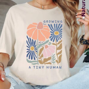 Schwangerschaft Shirt Growing A Tiny Human | Babybauch Shirt Blumen | T-Shirt für werdende Mama | Geschenk Schwangerschaft Party Baby Shower
